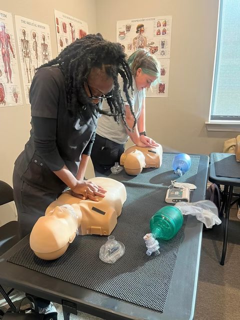 Two students performing CPR compressions on manikins